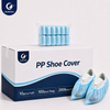 Justcare disposable PP shoe cover packaging display — a white carton box printed with the Justcare "PP Shoe Cover" logo, holding rolled blue shoe covers in transparent bags, beside a pair of white shoes wearing the blue shoe covers; pack sizes 10pcs/roll, 100pcs/bag and 2000pcs/ctn.