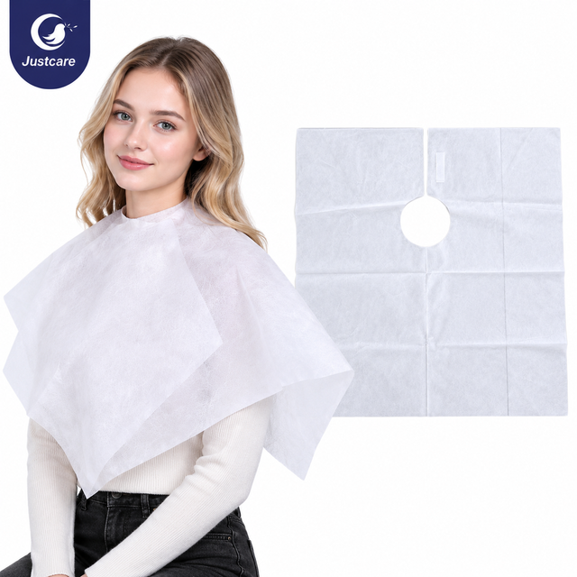 Justcare disposable white non-woven hair cutting cape wearing demo. Female model with salon cape, flat view of cape on right side, round neck opening with adjustable hook and loop, pure white background.